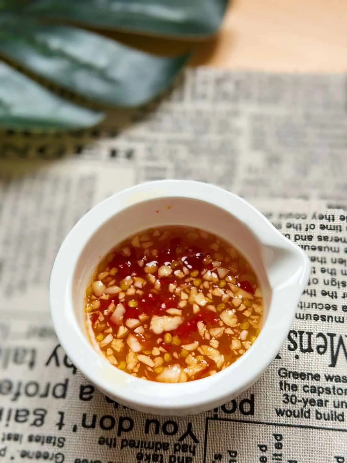 Vietnamese Spring Rolls with Peanut Sauce | Gỏi Cuốn A small white bowl filled with Vietnamese dipping fish sauce, with minced garlic and chili