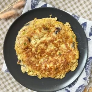 "Image of a Vietnamese-style omelette on a plate, with a golden brown exterior and a fluffy, yellow interior."