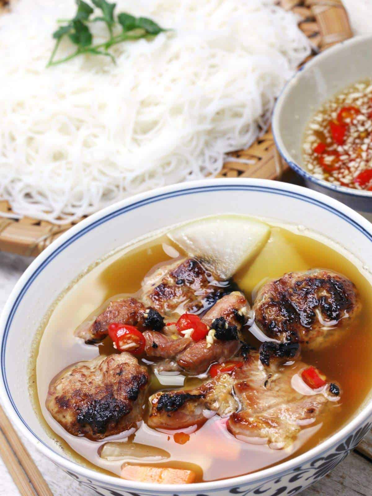 Hanoi Eats 2025: 13 Street Foods Locals Swear By A tempting photo of Bun Cha, featuring grilled pork patties, pork belly, vermicelli noodles, fresh herbs, and dipping sauce.