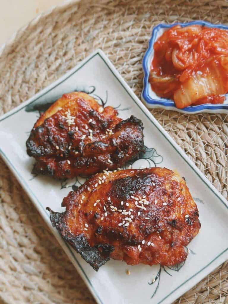 An enticing image of Air Fryer Gochujang Chicken Thighs, showcasing golden-brown, crispy chicken thighs coated in a delicious gochujang marinade. The dish is served with a garnish of sesame seeds.