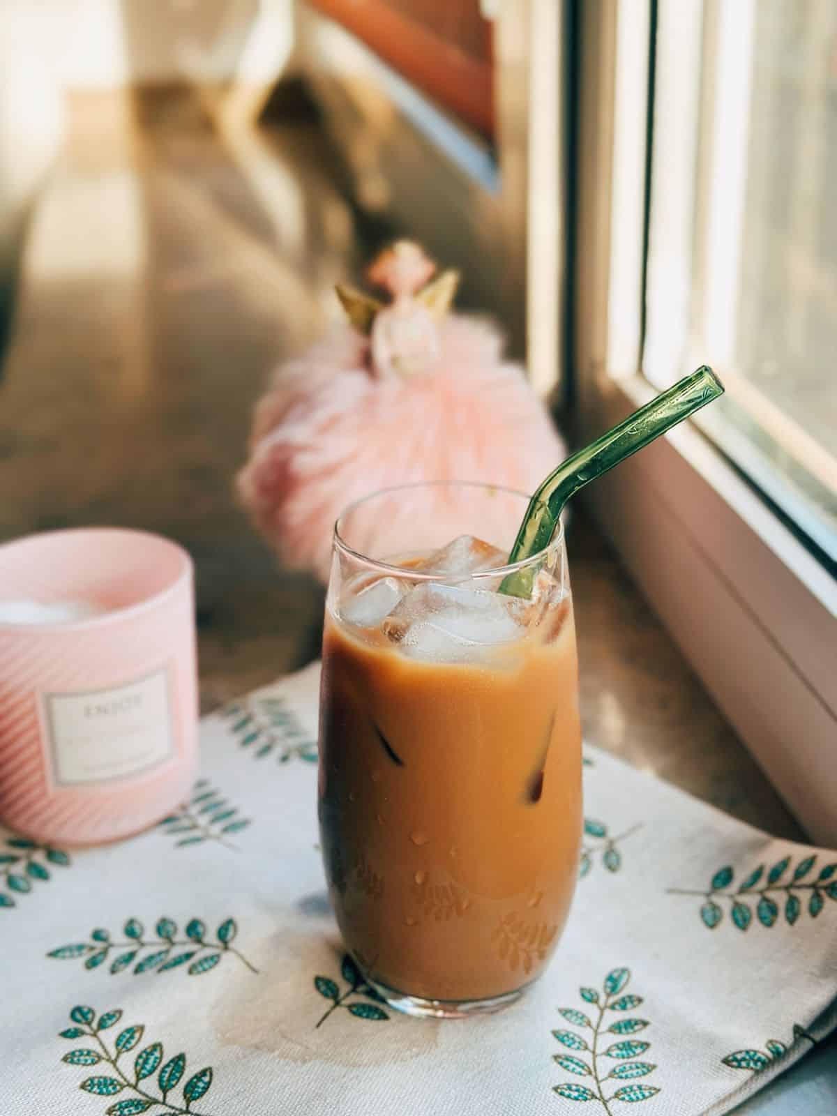 The Best Caramel Milk Tea (15-minute) An enticing photo of a steaming cup of caramel milk tea sitting on a sunlit windowsill. The sunlight streaming through the window casts a soft glow, highlighting the rich, inviting colors of the beverage.