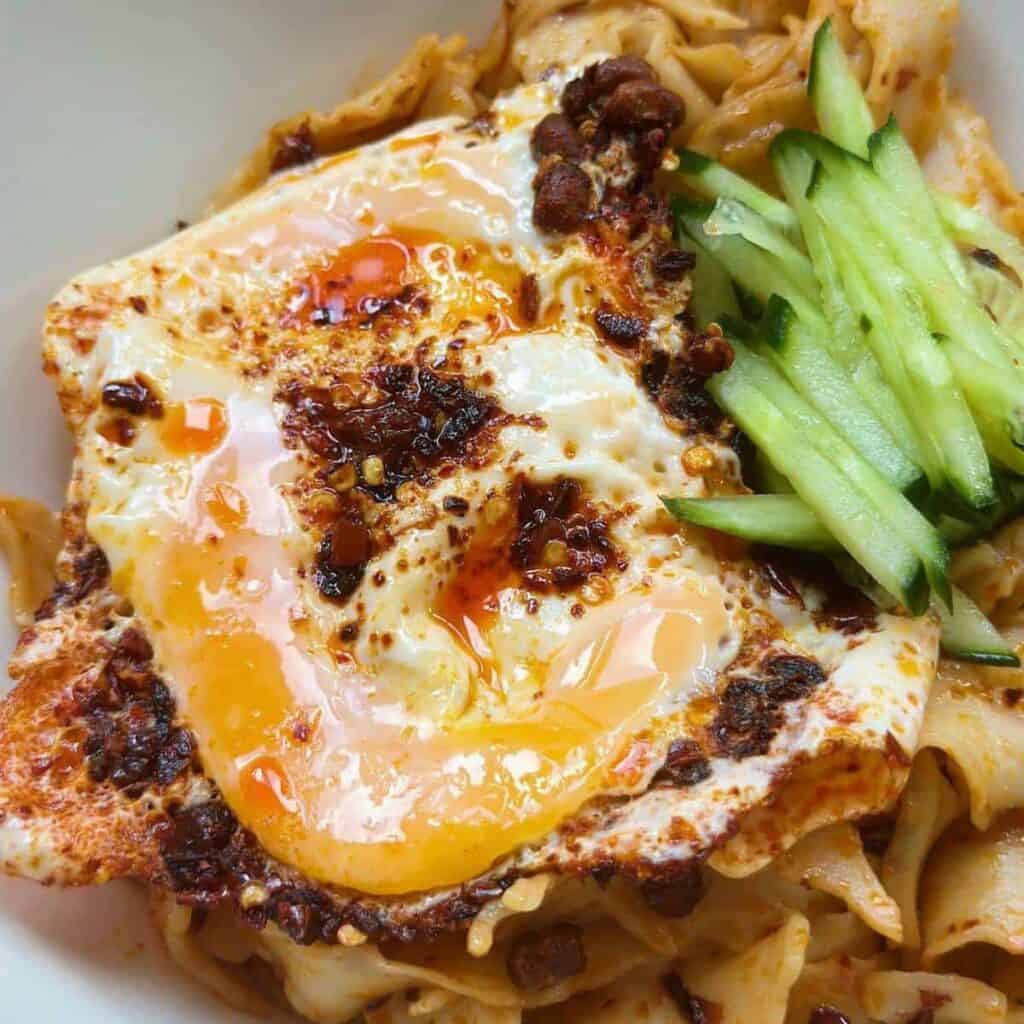 A visually enticing photo showcasing chili oil eggs prepared to perfection. The fried eggs are bathed in a rich, aromatic chili oil, creating a striking contrast of colors. The eggs have a golden, crispy exterior, while the chili oil adds a spicy and flavorful twist