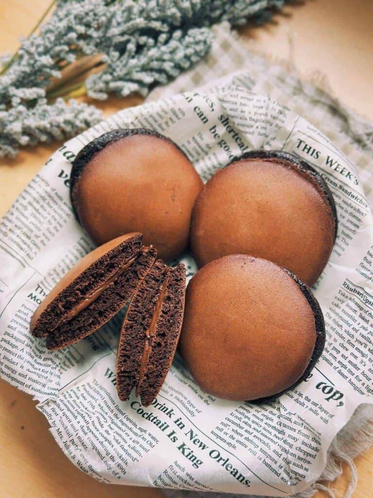 A close-up image of a delicious chocolate dorayaki dessert with a soft, golden pancake exterior and a luscious Nutella filling.