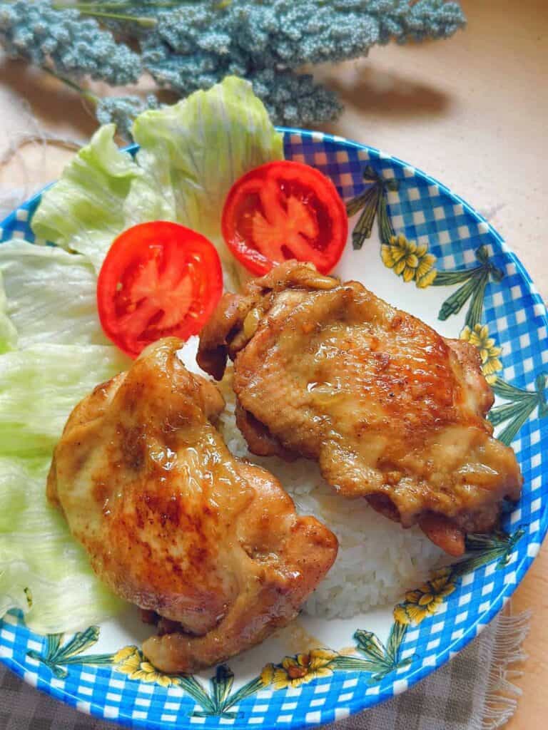 A plate of Com Ga Roti, featuring perfectly cooked chicken thighs glazed in a savory sauce, served with steamed rice. A delicious Vietnamese culinary delight."