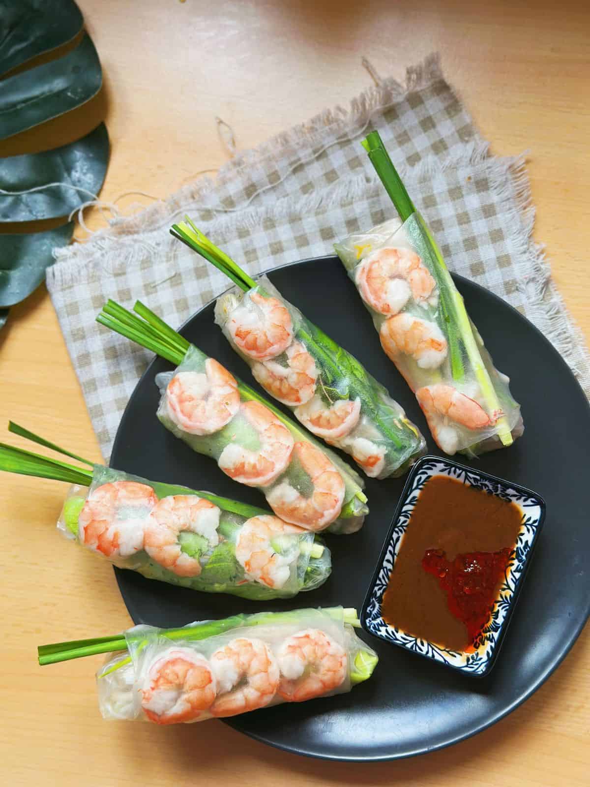 Delicious and refreshing Gỏi Cuốn - Vietnamese fresh spring rolls filled with succulent shrimp, tender slices of pork belly, crisp lettuce, rice vermicelli, and fragrant fresh herbs. Wrapped in translucent rice paper, these vibrant rolls are served with a tantalizing dipping sauce.