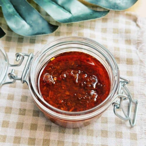 Sate Sauce - Vietnamese Lemongrass Chili Oil Close-up photo of a jar filled with vibrant red Vietnamese Sate Sauce or Vietnamese Chili Oil, showcasing its rich and spicy aroma. The sauce is made from crushed chili peppers, lemongrass, garlic, and other flavorful ingredients, adding a delightful kick to Vietnamese cuisine.