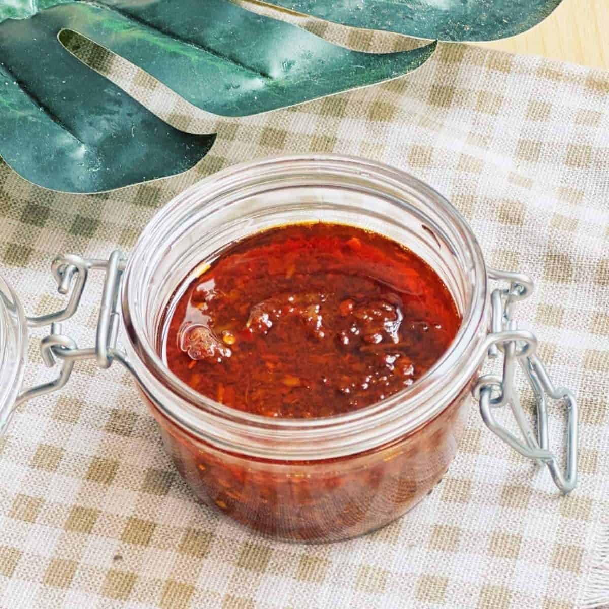 Close-up photo of a jar filled with vibrant red Vietnamese Sate Sauce or Vietnamese Chili Oil, showcasing its rich and spicy aroma. The sauce is made from crushed chili peppers, lemongrass, garlic, and other flavorful ingredients, adding a delightful kick to Vietnamese cuisine.