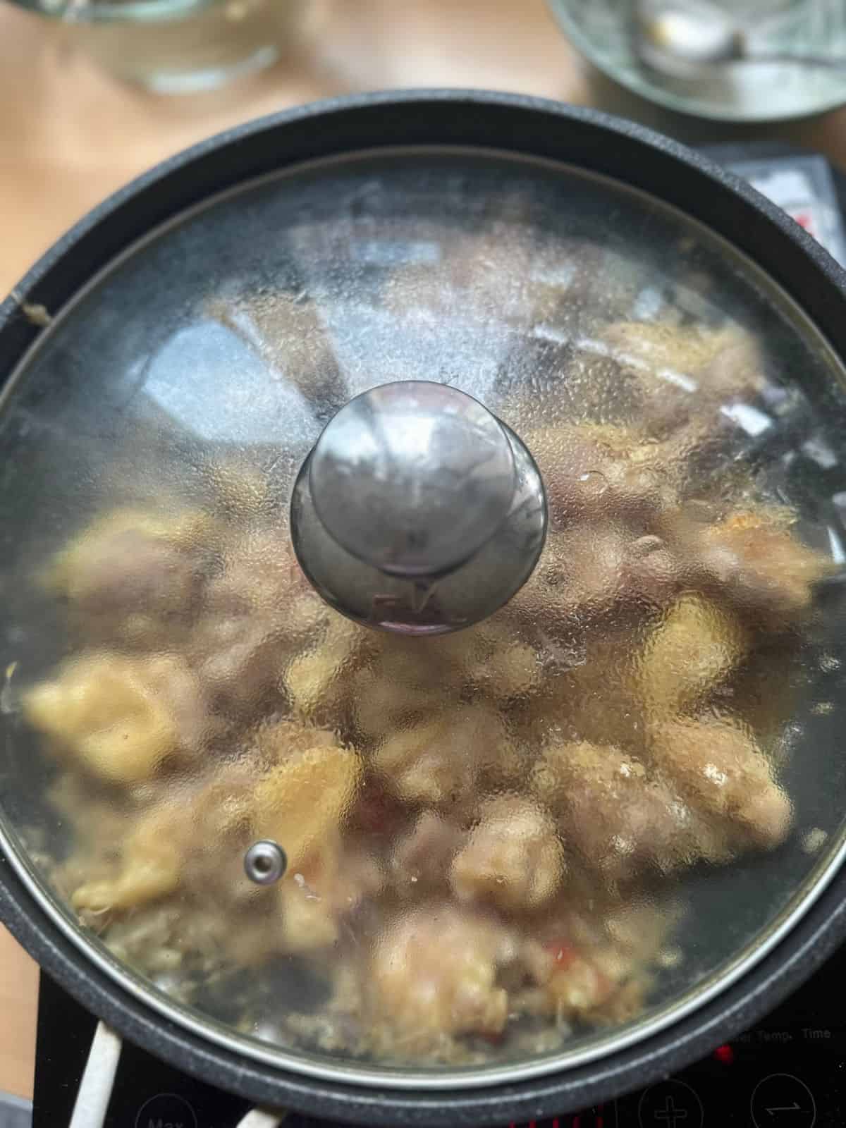 Mom's Easy Gà Xào Xả Ớt (Spicy Lemongrass Chicken) a pan of spicy lemongrass chicken with a lid placed on top.