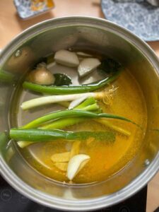 onion, scallion, ginger, kaffir leaves, turmeric powder in a pot of water