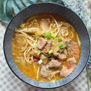 Phở Sate (Spicy Beef Satay Pho) Steaming bowl of Pho Sa Tế with flat rice noodles, rich satay broth, and an assortment of fresh toppings