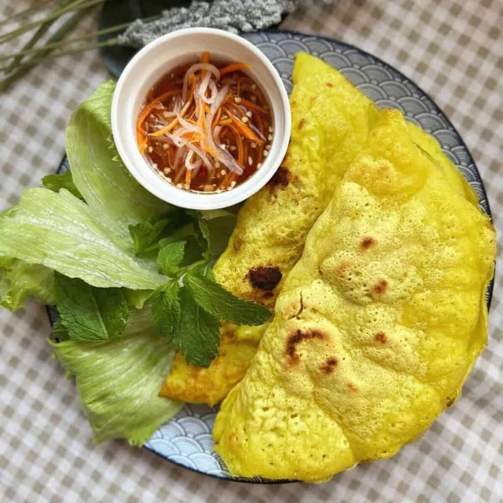 Vietnamese Sweet & Sour Soup (Canh Chua Cá) Bánh Xèo - Vietnamese sizzling crepes with shrimp, pork, and mung bean sprouts, served with fresh herbs and dipping sauce.