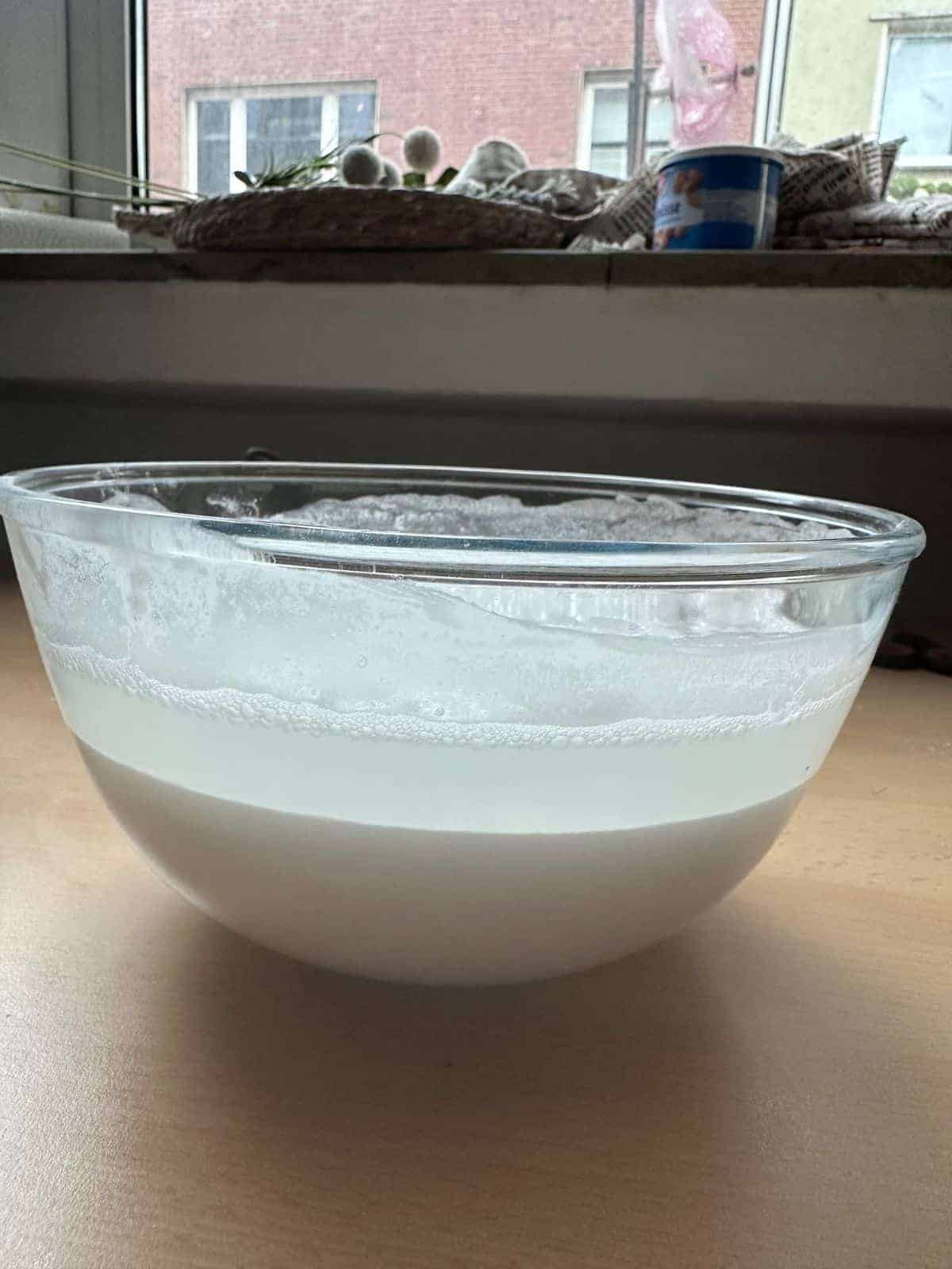 Vietnamesische gedämpfte Reisrollen (Bánh Cuốn) A bowl of batter which is separated into 2 layers of flour and water.