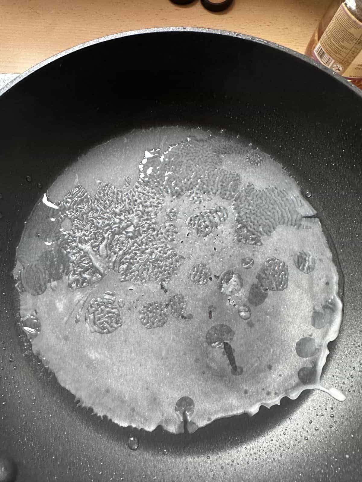 Vietnamesische gedämpfte Reisrollen (Bánh Cuốn) Rotate and tilt the nonstick skillet to create a thin layer of rice sheet.