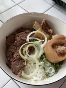 A bowl of rice noodles and meat for Bún Bò Huế.