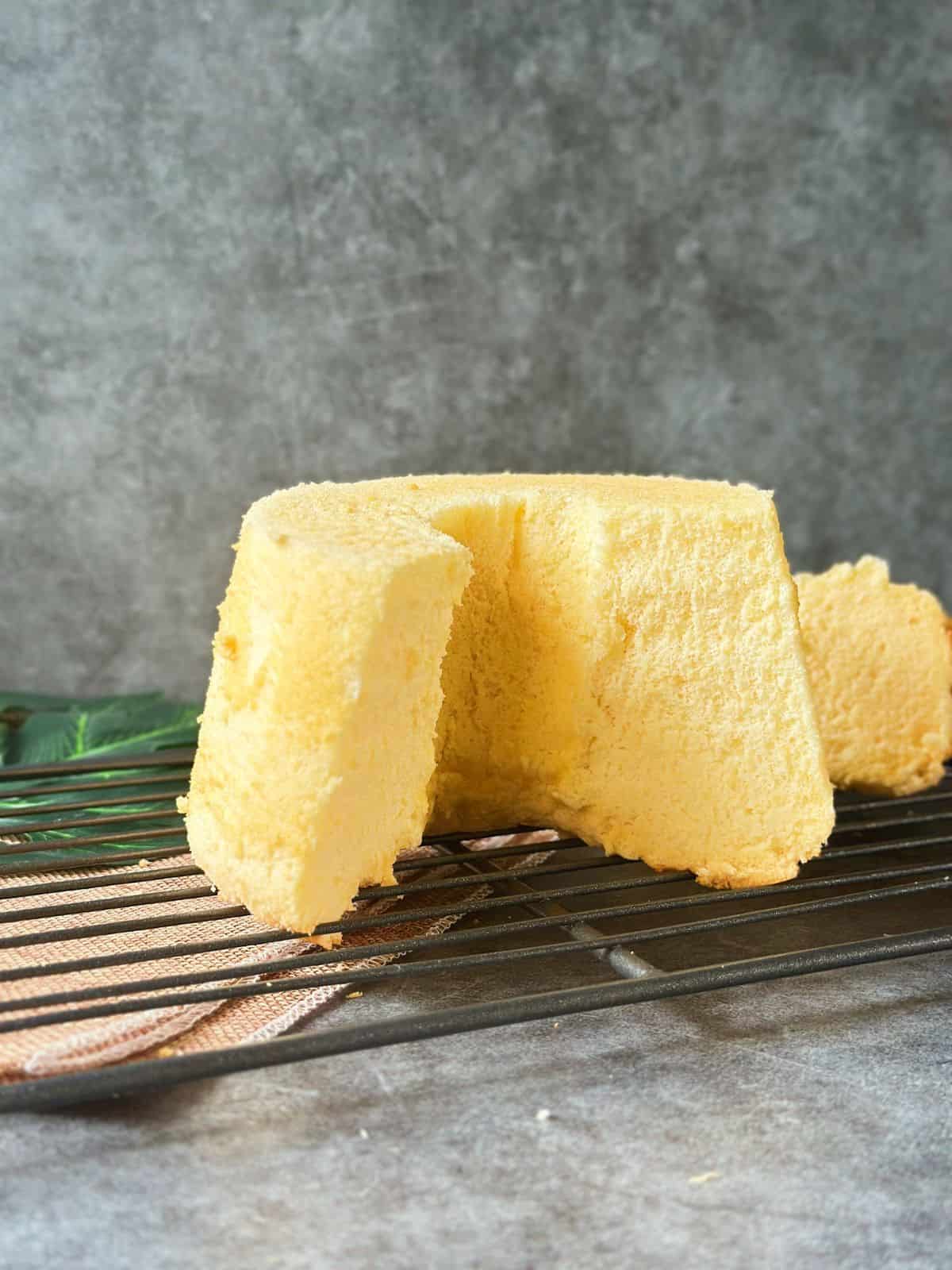 Fluffiger Chiffon Kuchen / Chiffon Cake / シフォンケーキ A tall, fluffy Chinese chiffon cake on a cooling rack, with one large slice cut out to show its soft, airy texture.