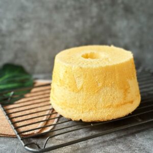 Fluffiger Chiffon Kuchen / Chiffon Cake / シフォンケーキ A side view of a golden-brown Chinese chiffon cake on a cooling rack, showing its smooth, pillowy surface and height.