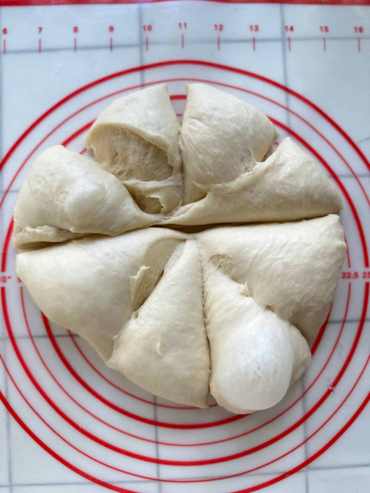 Soft dough divided into 8 equal portions, ready to be shaped for baking.