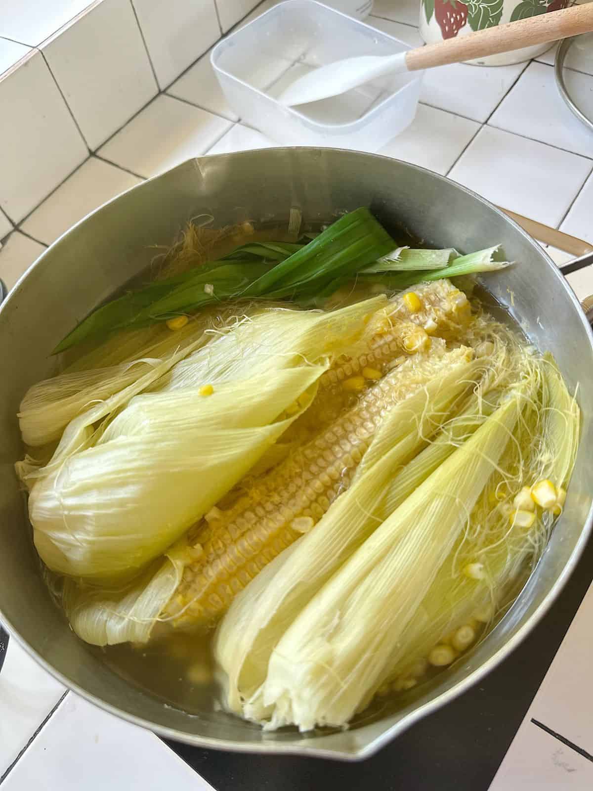 Corn Milk (Vietnamese Sữa Bắp) orn cobs, husks, and pandan leaves simmering in a pot – step-by-step Vietnamese corn milk recipe.