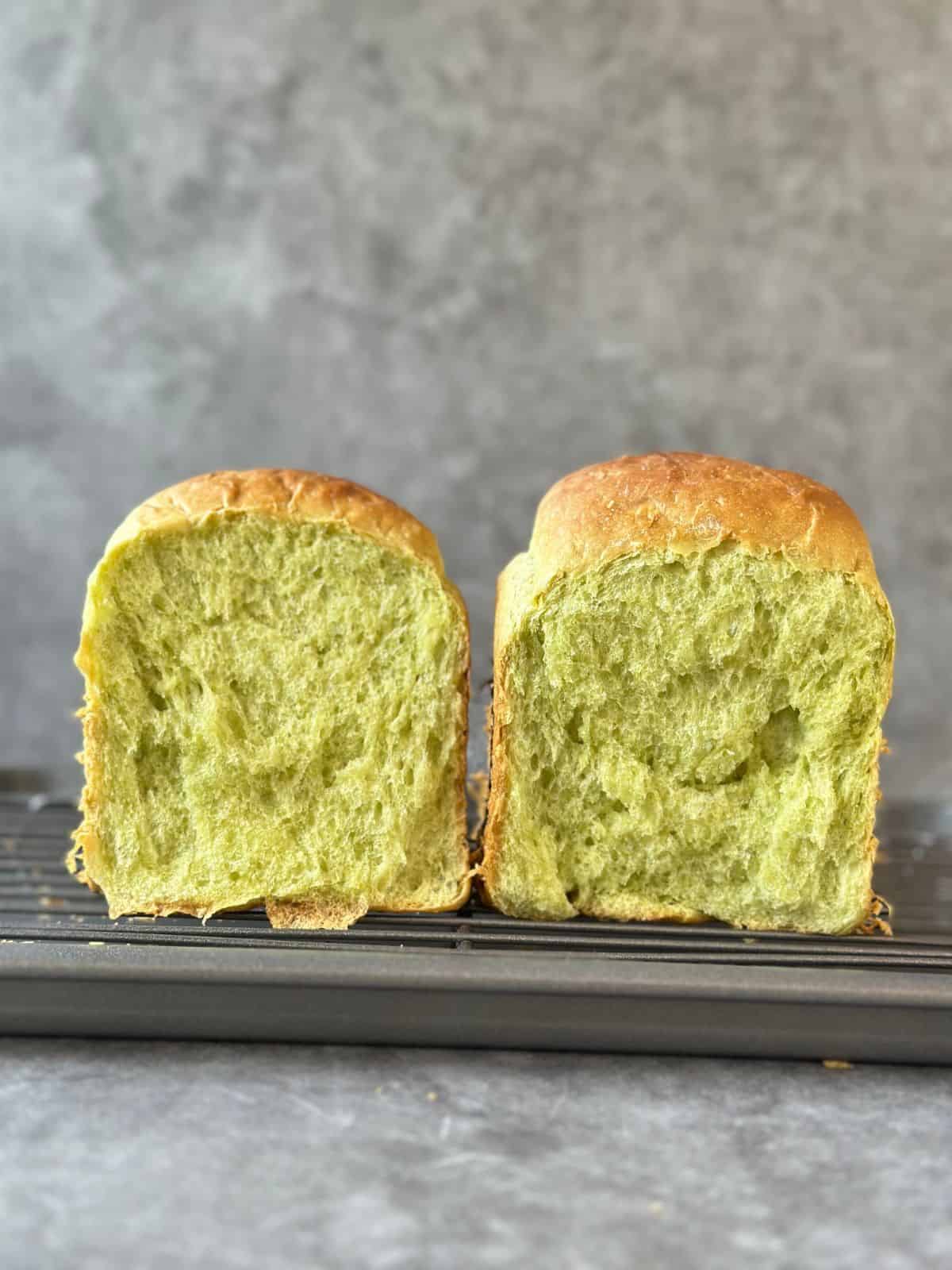 Pillow-Soft Pandan Bread (Vegan) Two halves of a pandan bread loaf, revealing a light and airy green interior.