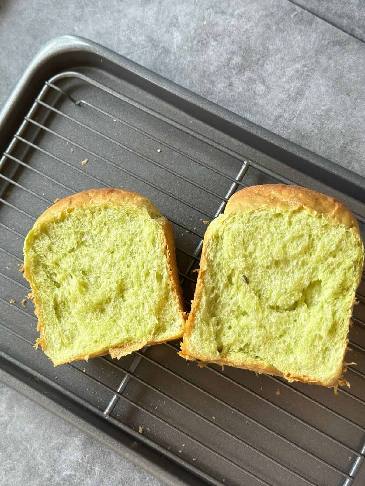 Pillow-Soft Pandan Bread (Vegan) Two slices of pandan bread on a cooling rack, showing the soft, fluffy texture.