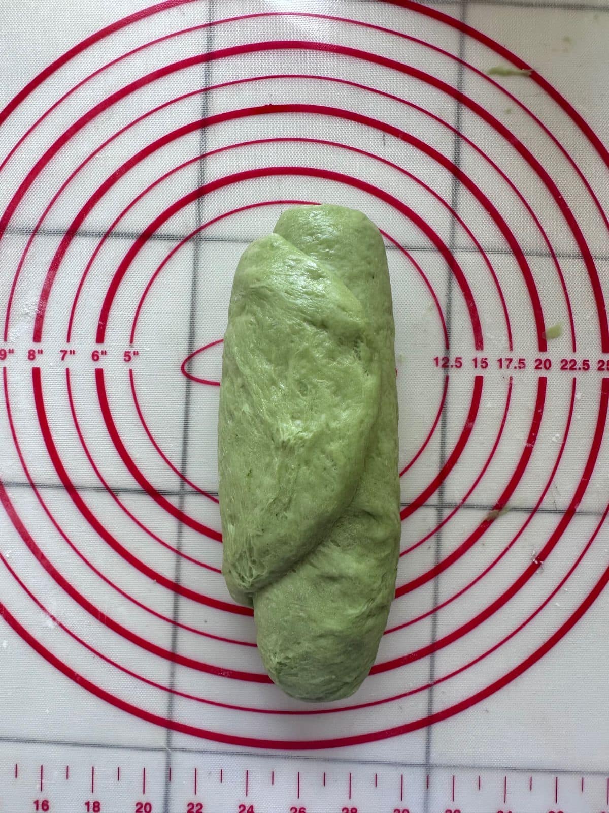 Pillow-Soft Pandan Bread (Vegan) Green dough twisted into a short loaf shape with overlapping ends on the silicone mat.