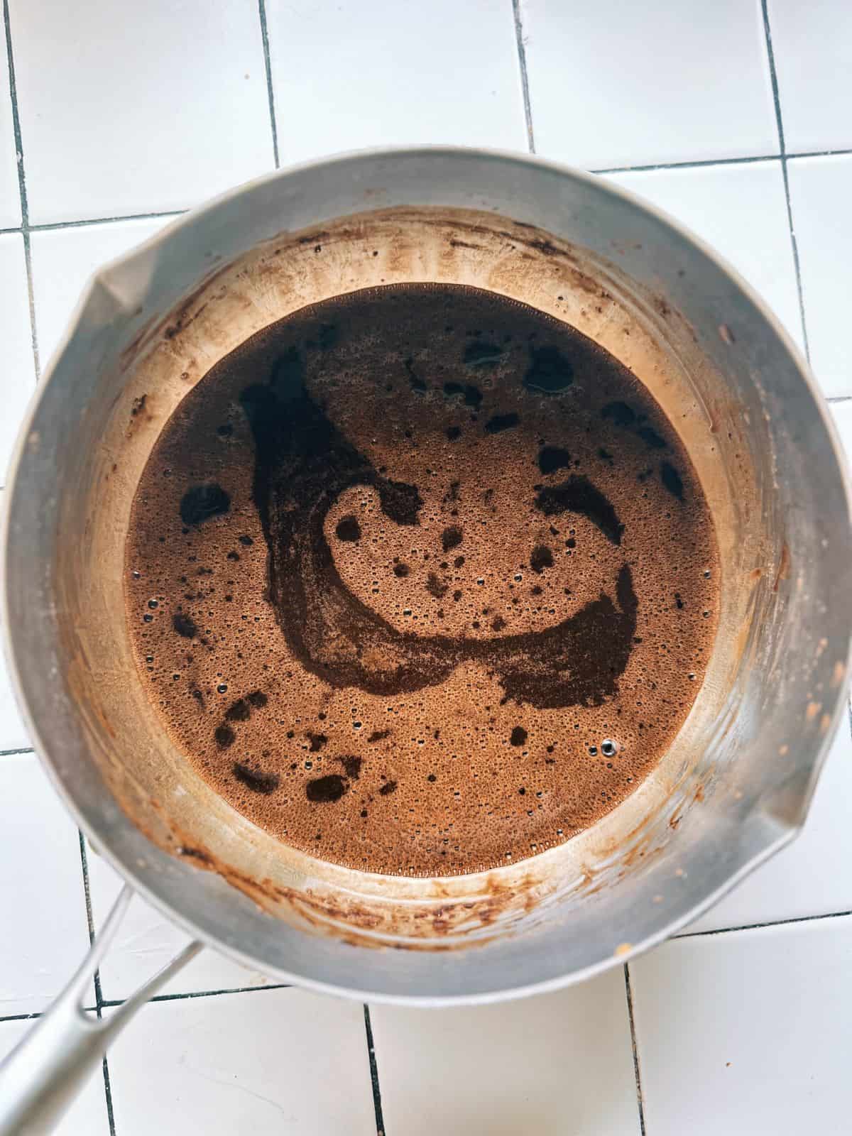 Grass jelly powder, tapioca starch, and sugar mixed with water in a pot before cooking.
