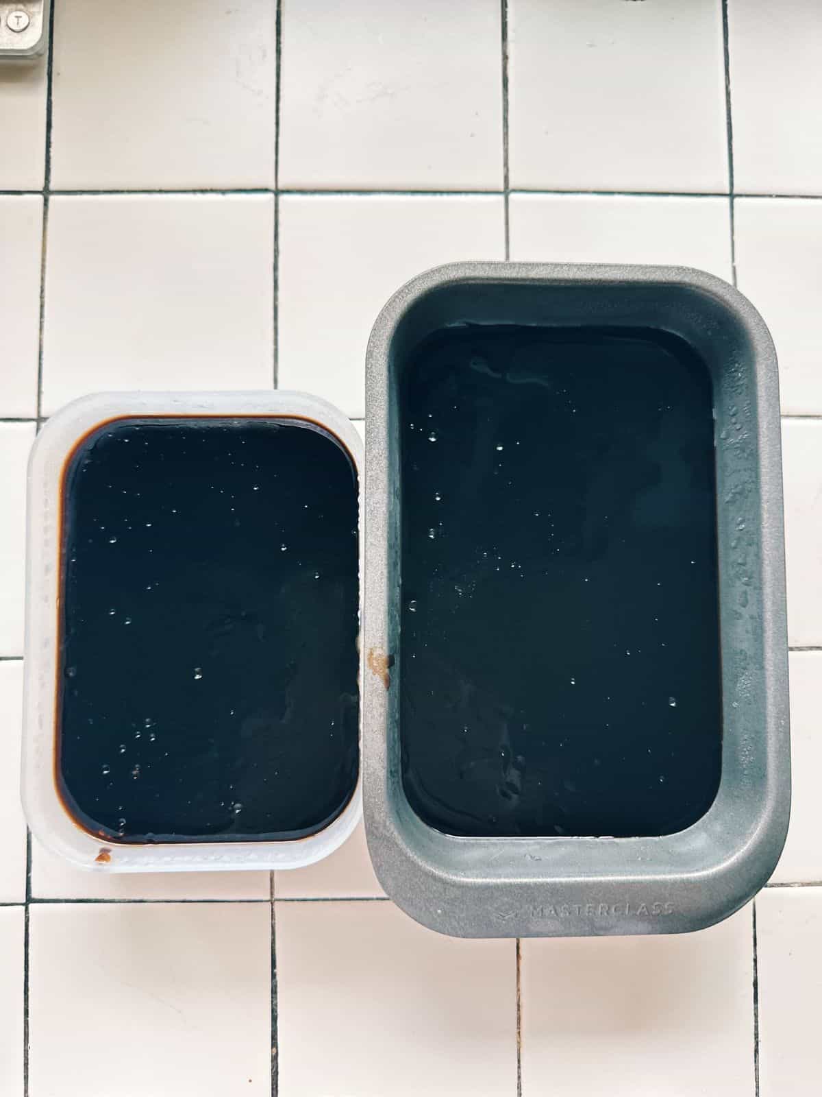 Hot grass jelly mixture being poured into two molds through a sieve.