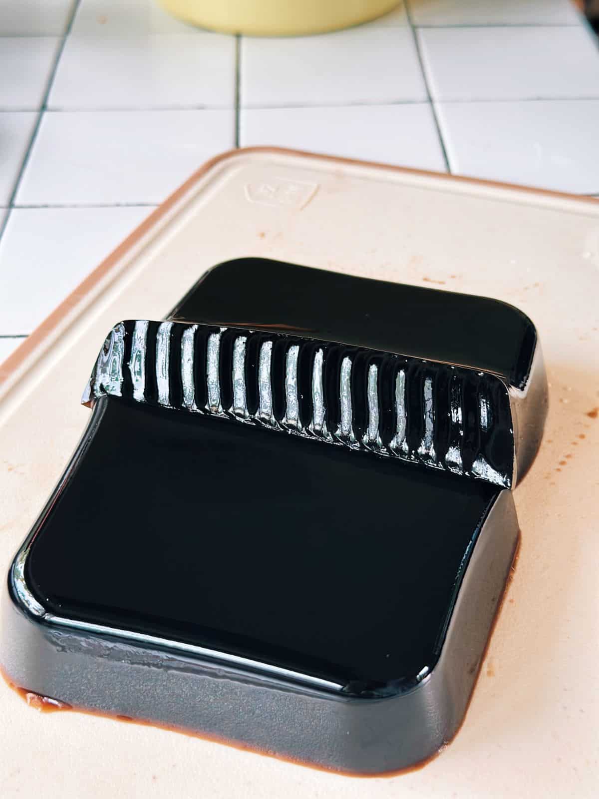 Grass jelly block cut in half, showing its shiny surface.