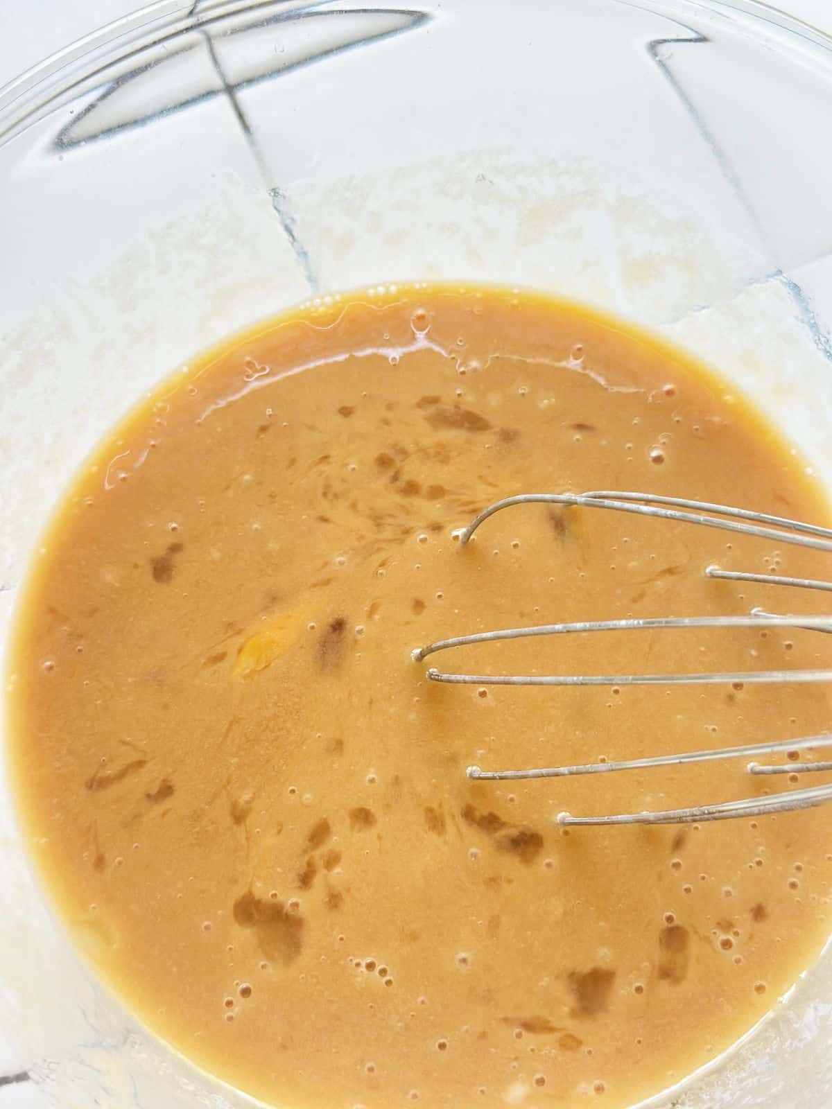 Beaten eggs in a glass mixing bowl.