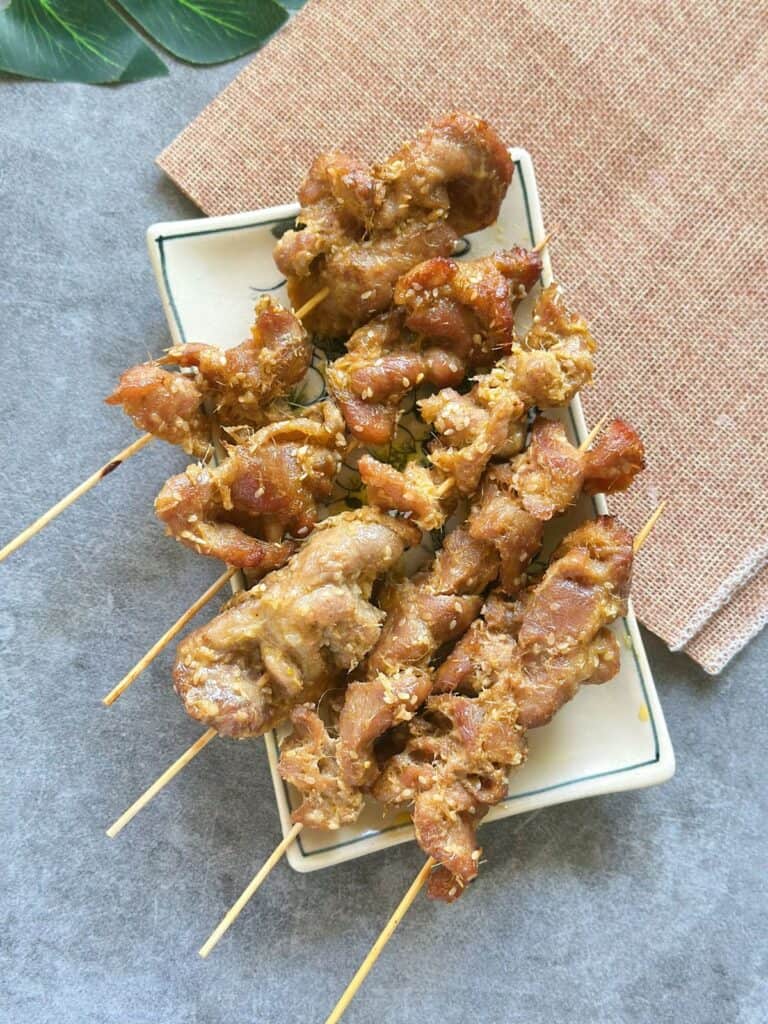 Juicy Vietnamese grilled pork skewers served on a plate, garnished with sesame seeds