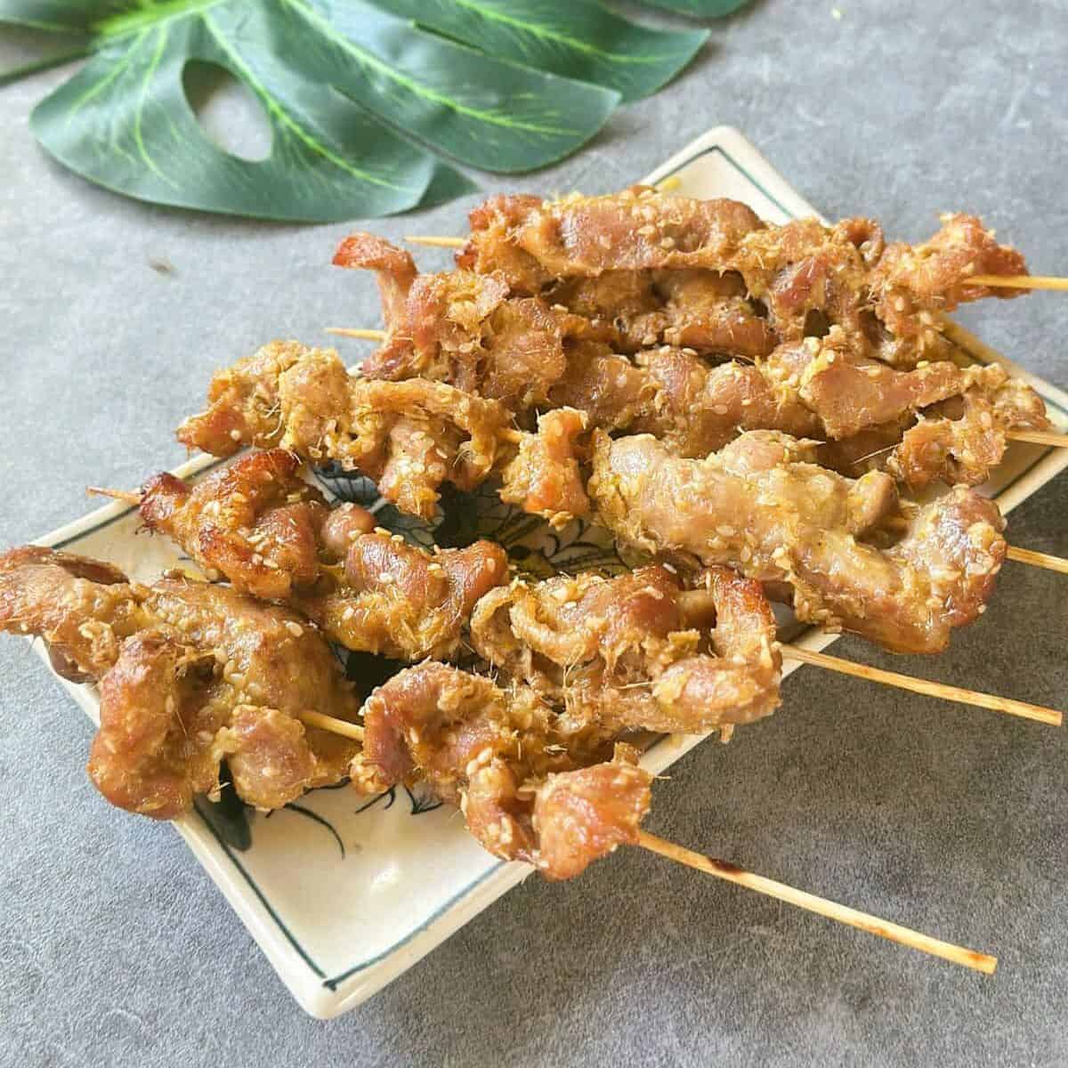 Juicy Vietnamese grilled pork skewers served on a plate, garnished with sesame seeds
