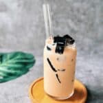 Glass of Vietnamese milk tea served over ice with cubes of grass jelly.