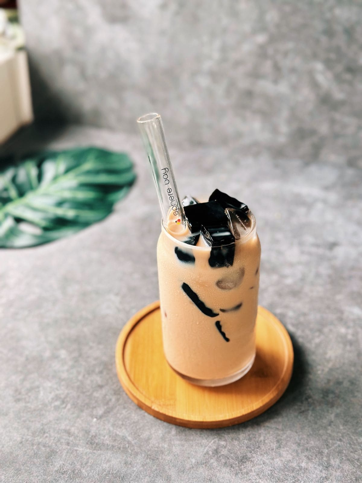 Glass of Vietnamese milk tea served over ice with cubes of grass jelly.