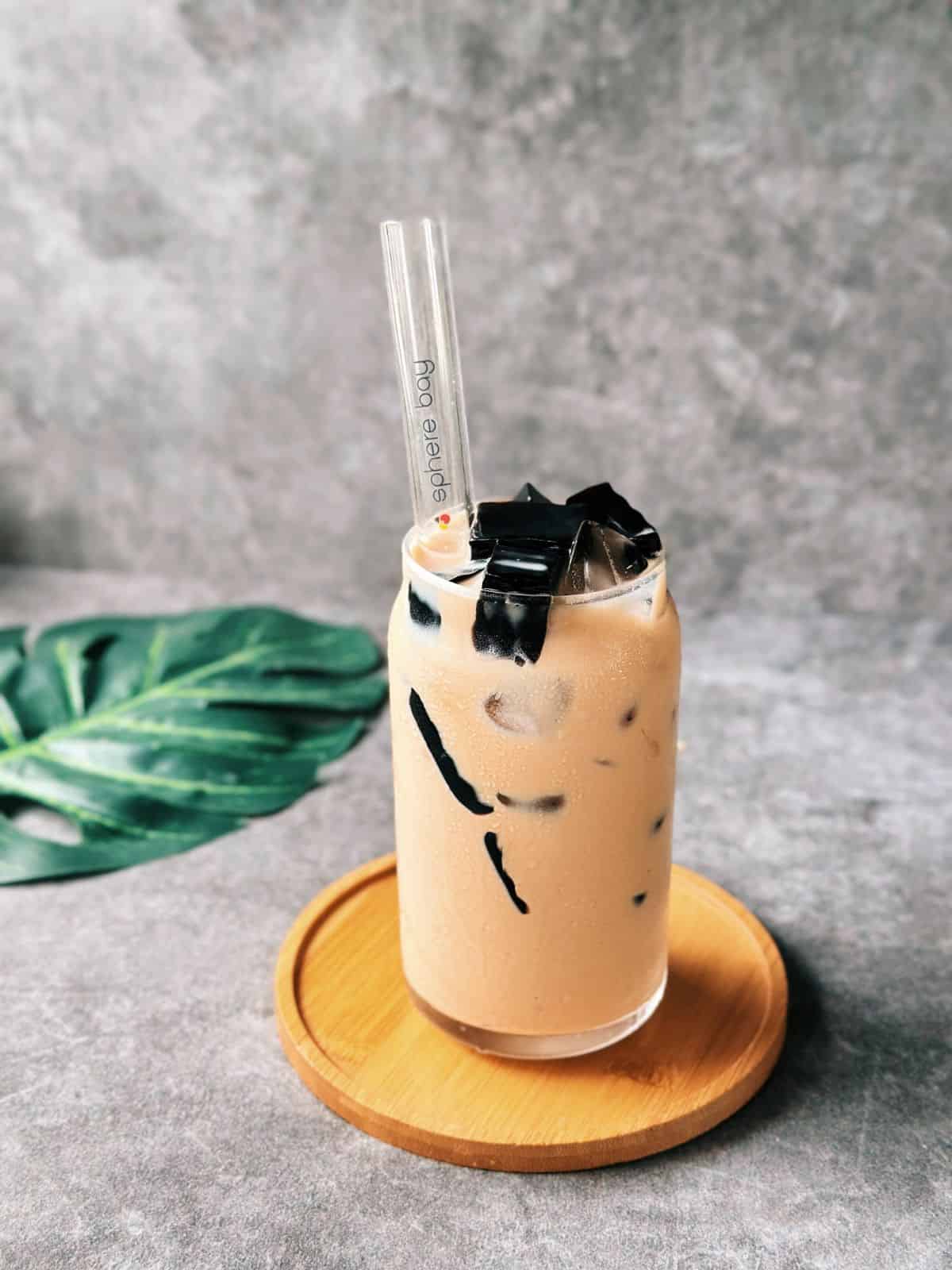 Glass of Vietnamese milk tea with grass jelly cubes and ice.