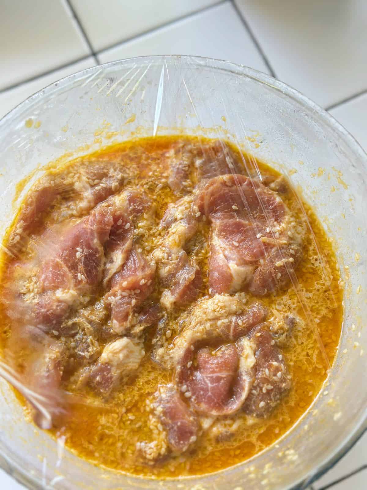 Thinly sliced pork shoulder marinated with lemongrass, garlic, fish sauce, and spices in a mixing bowl