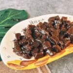A plate of glossy, cooked boba pearls coated in syrup, glistening and ready to add to milk tea.
