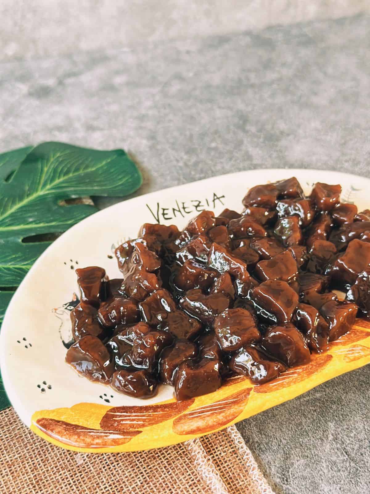 A plate of glossy, cooked boba pearls coated in syrup, glistening and ready to add to milk tea.