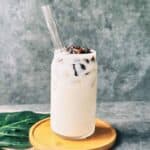 Iced jasmine milk tea served in a clear glass, topped with glossy boba pearls.