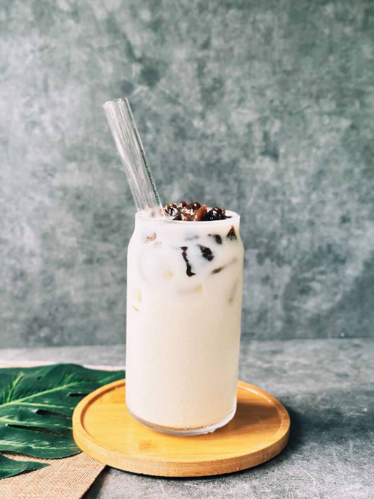 Iced jasmine milk tea served in a clear glass, topped with glossy boba pearls.