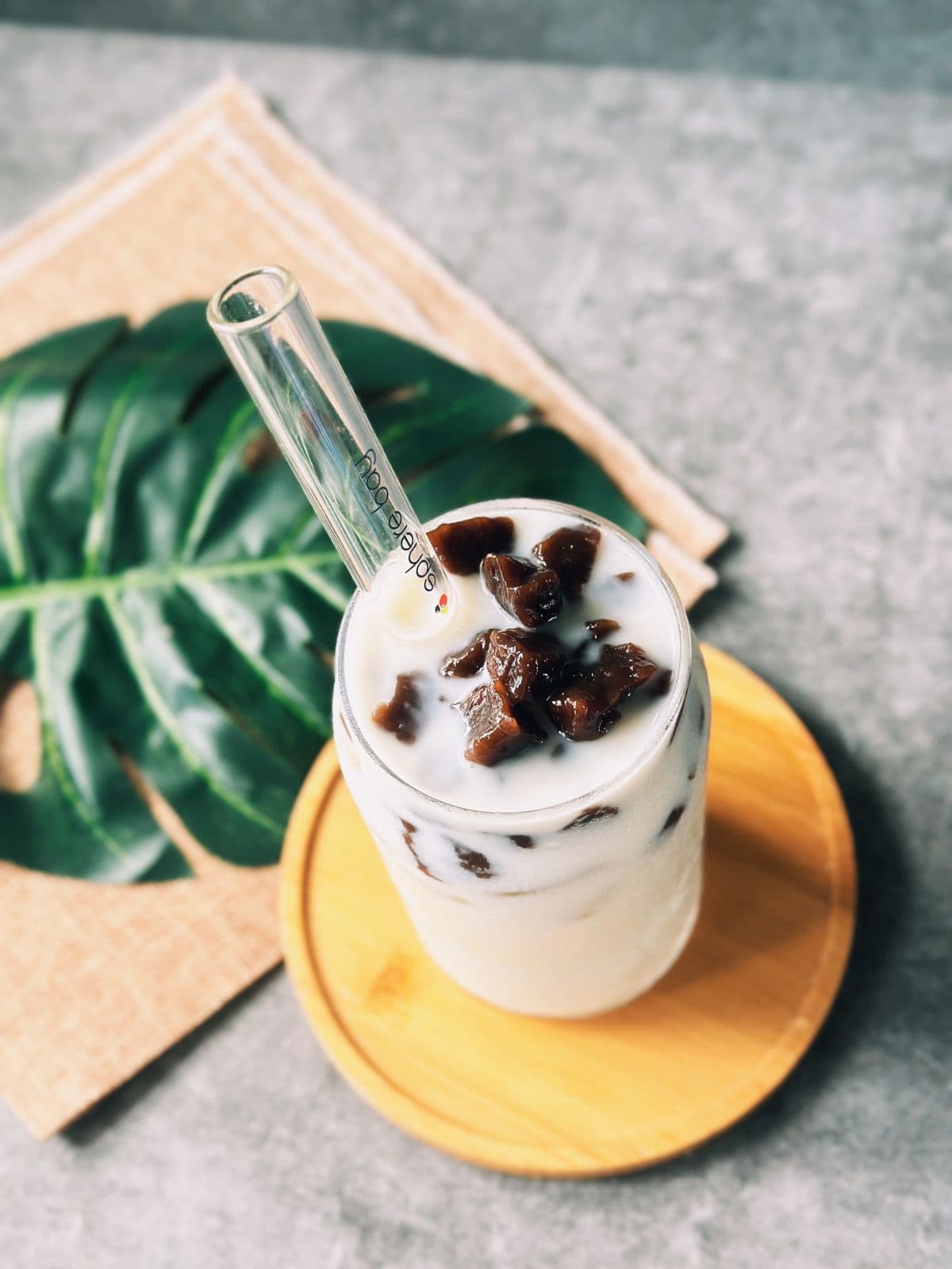 Iced jasmine milk tea served in a clear glass, topped with glossy boba pearls.