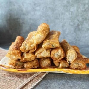 A plate filled with crispy golden Vietnamese fried spring rolls (Nem Rán), freshly fried and ready to serve.