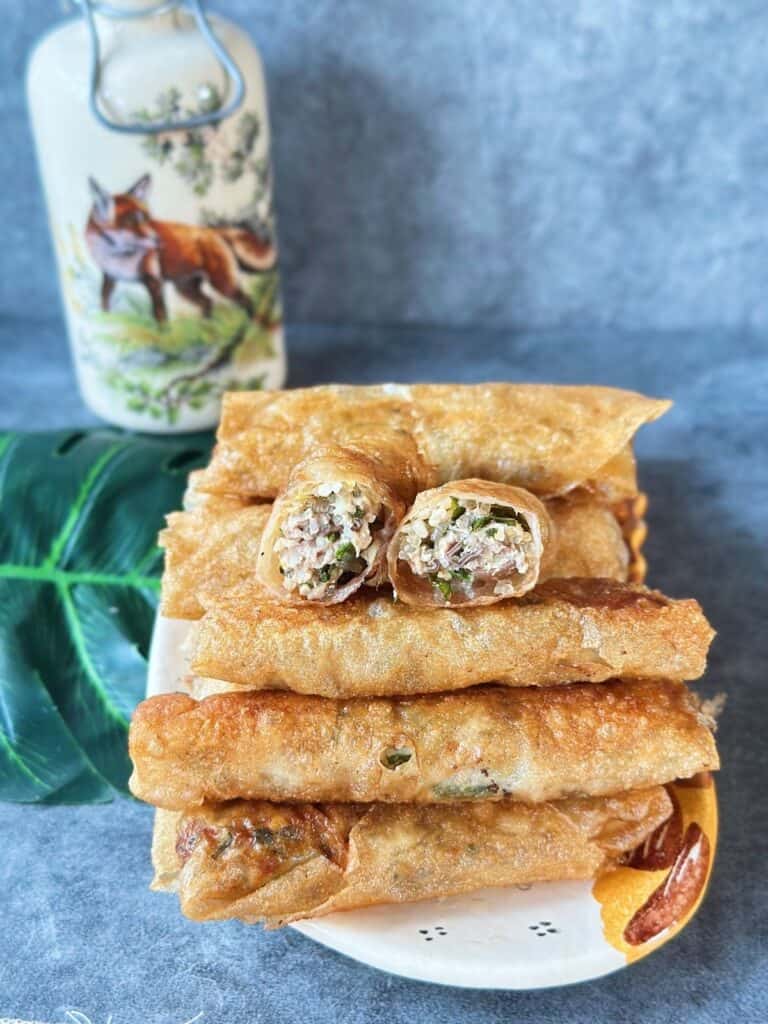 A plate filled with crispy golden Vietnamese fried spring rolls (Nem Rán), freshly fried and ready to serve.