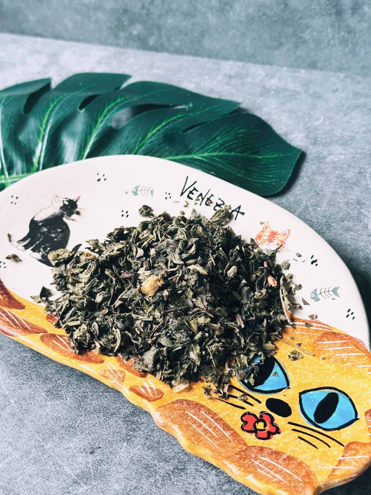 Dried jasmine tea leaves on a plate, showing their delicate green color and floral buds.