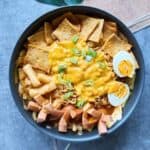 Pfanne mit würzigem Rabokki – koreanische Reiskuchen (Tteokbokki) und Ramyeon in roter Gochujang-Soße, mit Fischkuchen, Wurst, Ei, Lauch und geschmolzenem Käse garniert.