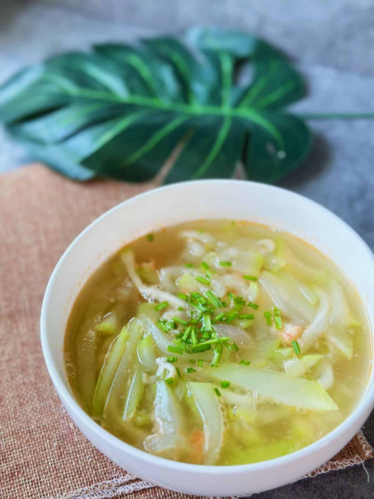 A bowl of Canh Bầu Tôm with tender opo squash, chopped shrimp, and scallions floating in a light, fragrant soup.