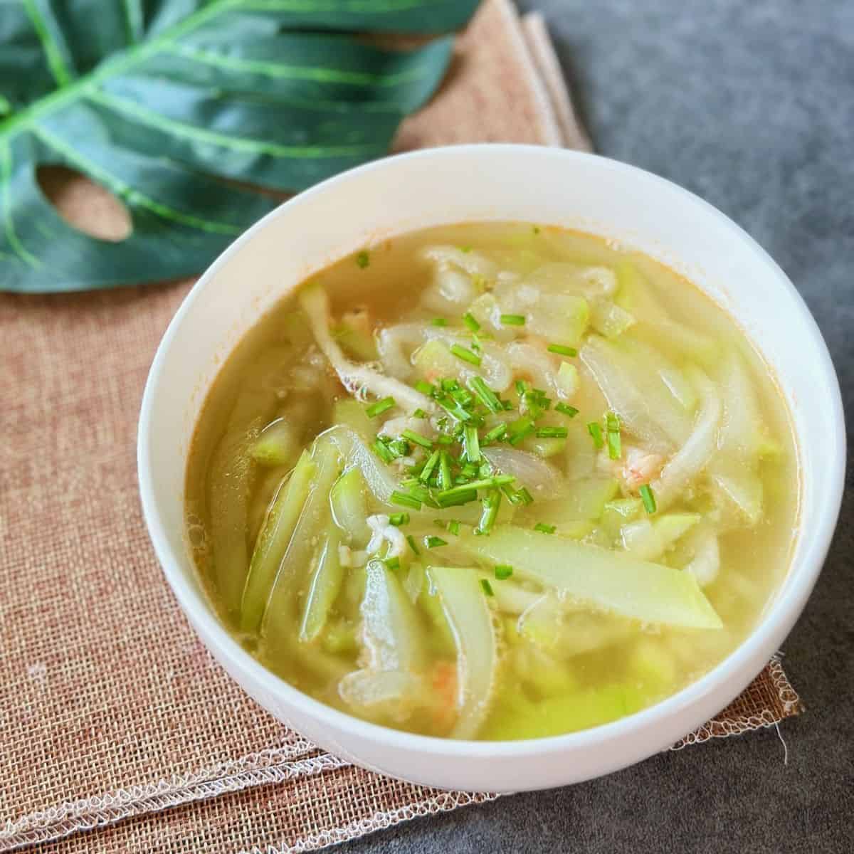 A bowl of Canh Bầu Tôm with tender opo squash, chopped shrimp, and scallions floating in a light, fragrant soup.