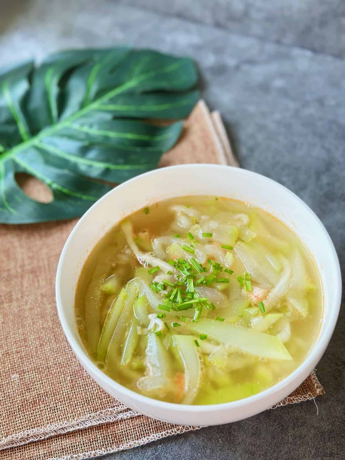 A bowl of Canh Bầu Tôm with tender opo squash, chopped shrimp, and scallions floating in a light, fragrant soup.
