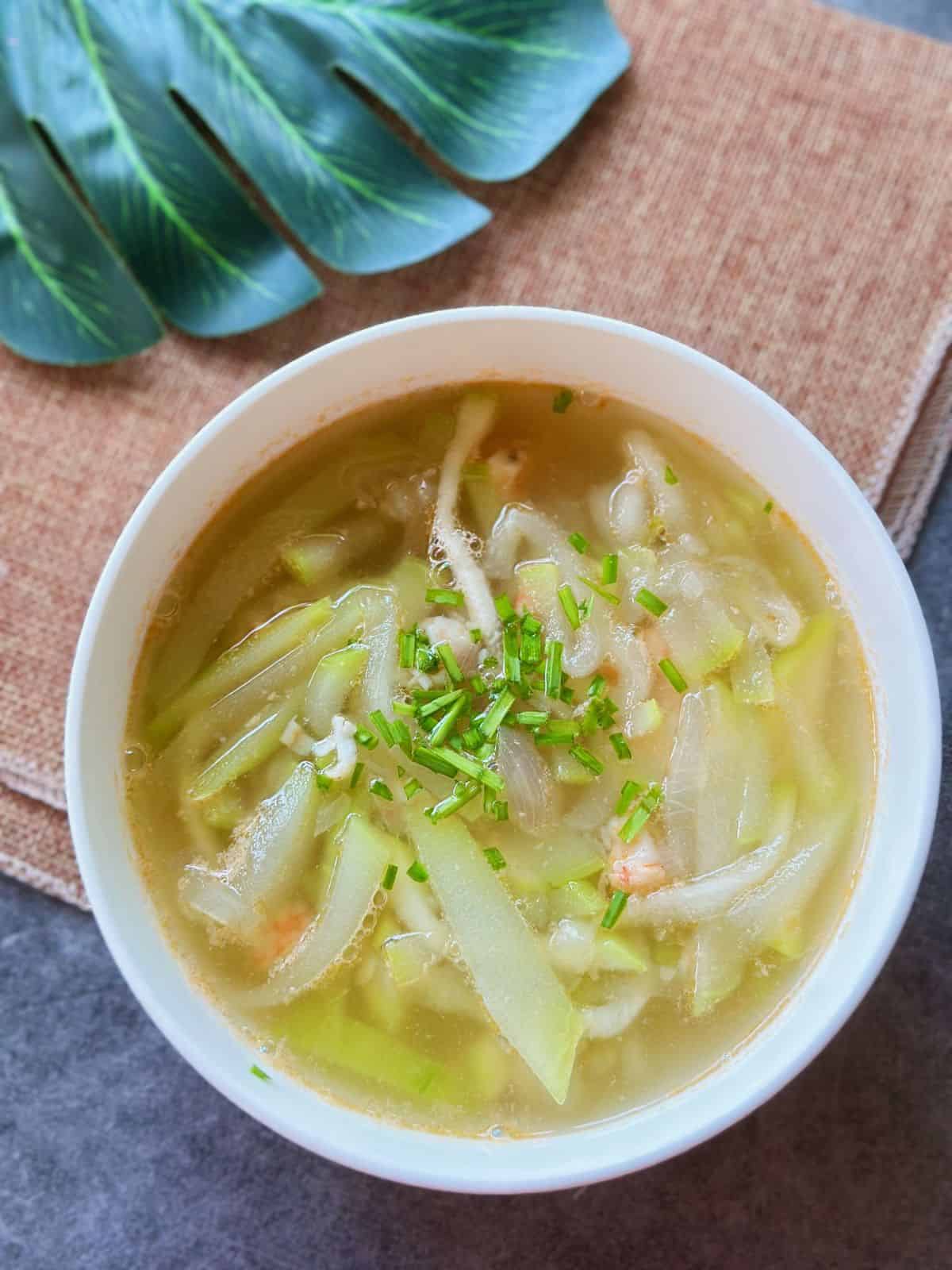 A bowl of Canh Bầu Tôm with tender opo squash, chopped shrimp, and scallions floating in a light, fragrant soup.