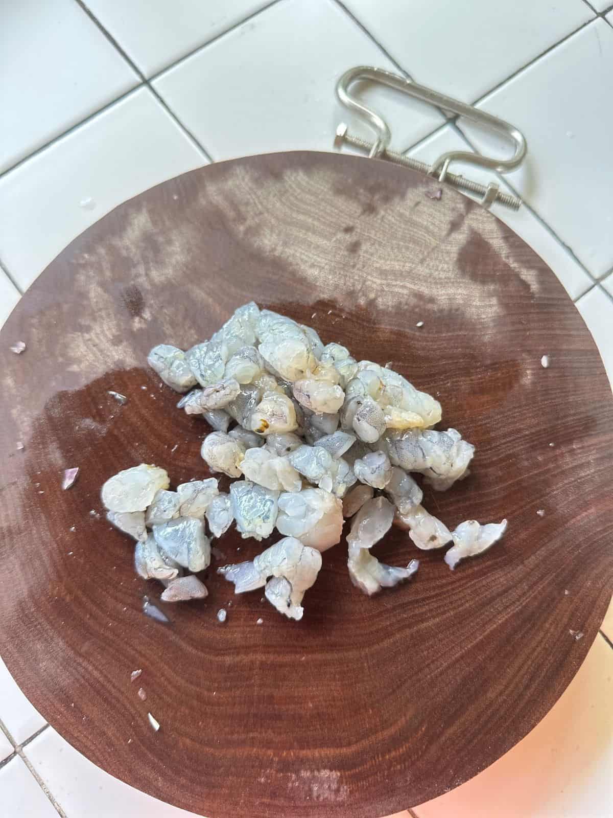Chopped shrimp on a wooden cutting board, ready for cooking.