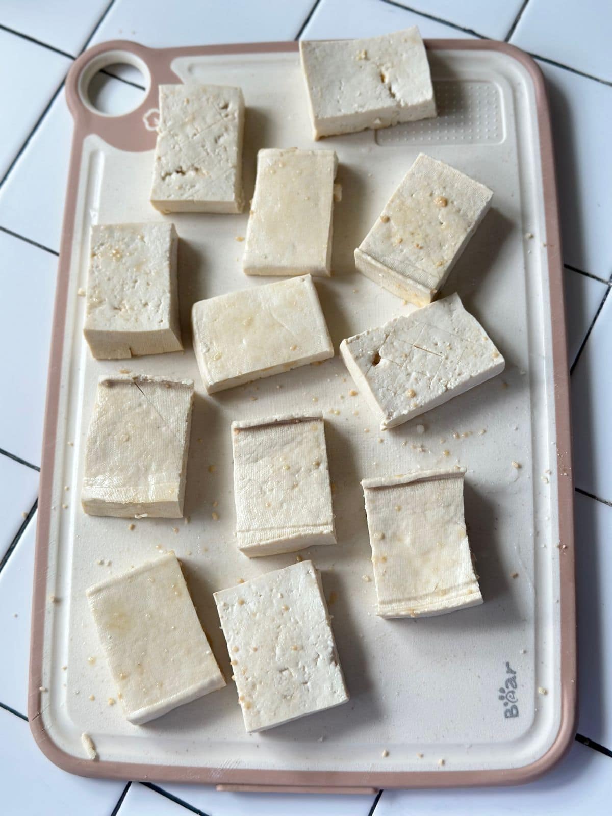 Pieces of tofu marinated and arranged on a cutting board.